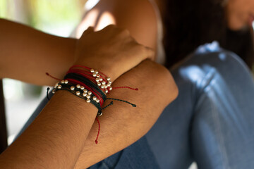 woman's hand with red and gold bracelet on jean pants