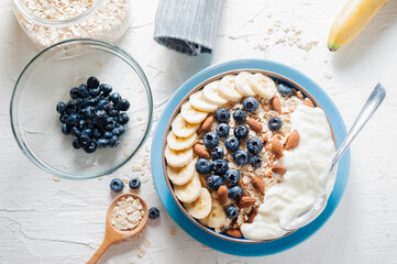 Breakfast, oatmeal with blueberry, banana almond and yogurt on a bowl in the morning.