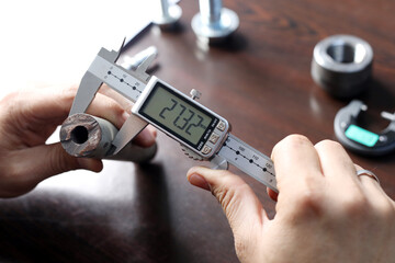 Worker is measuring to the diameter of the small pipe with a digital vernier caliper micrometer....