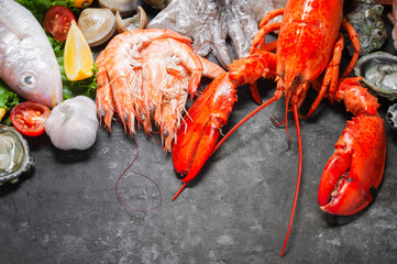 Shellfish and crustacean seafood with selection of fresh lobster, shrimp, fish, oyster, squid and crab on dark rustic background.