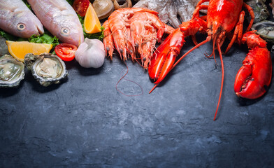 Shellfish and crustacean seafood with selection of fresh lobster, shrimp, fish, oyster, squid and crab on dark rustic background.