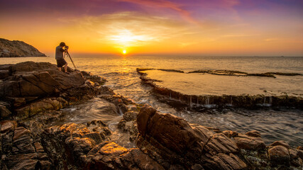 Photographer standing on the rock at Hang Rai Beach.Nui Chua national park, Ninh Thuan,Vietnam,amazing landscape when the waves on a large rock and make an wonderful waterfall