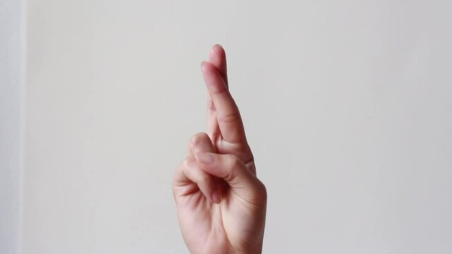 Female one hand holding two fingers up in sign language. Fingers crossed.