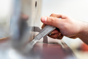 The inspector measures fillet weld thickness of the steel structure with gauge in the workshop.