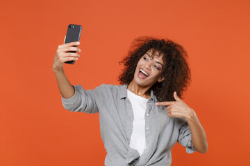Excited young african american woman in casual clothes isolated on orange background. People...