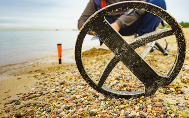 Man with metal detector on sea beach