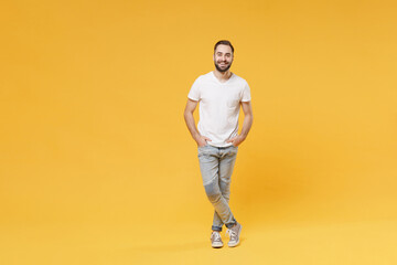 Smiling young bearded man guy in white casual t-shirt posing isolated on yellow background studio...