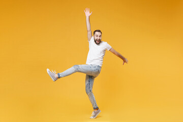 Fototapeta na wymiar Excited young bearded man guy in white casual t-shirt posing isolated on yellow wall background studio portrait. People emotions lifestyle concept. Mock up copy space. Rising spreading hands and legs.