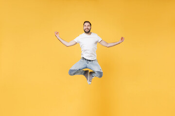 Fototapeta na wymiar Smiling young bearded man guy in white casual t-shirt posing isolated on yellow background studio. People lifestyle concept. Mock up copy space. Jumping hold hands in yoga gesture relaxing meditating.