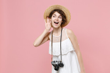 Curious tourist woman in summer dress hat photo camera isolated on pink background. Traveling...