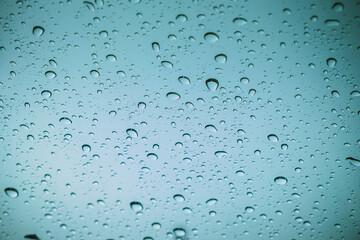 Colourful drops of rain on a window glass in the city. Image of raindrops texture background.