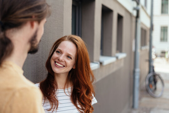 Happy young woman chatting to a man in the street