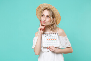 Pensive woman in white dress hat hold female periods calendar for checking menstruation days...