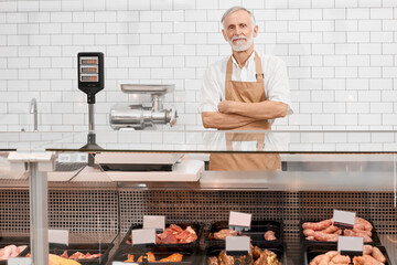 Male butcher posing behind counter.