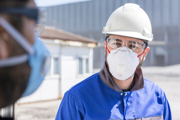 The worker (staff, engineer) protects himself from covid-19 (coronavirus) with a protective mask in the construction site.