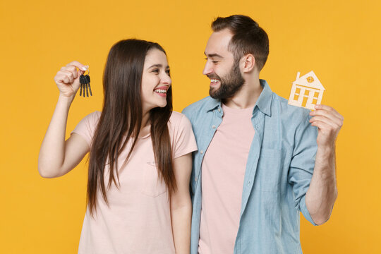 Smiling Young Couple Friends Guy Girl In Pastel Blue Casual Clothes Posing Isolated On Yellow Background. People Lifestyle Concept. Mock Up Copy Space. Hold House Bunch Of Keys Looking At Each Other.