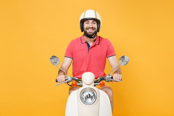 Smiling young bearded man guy in casual summer clothes helmet driving moped isolated on yellow...