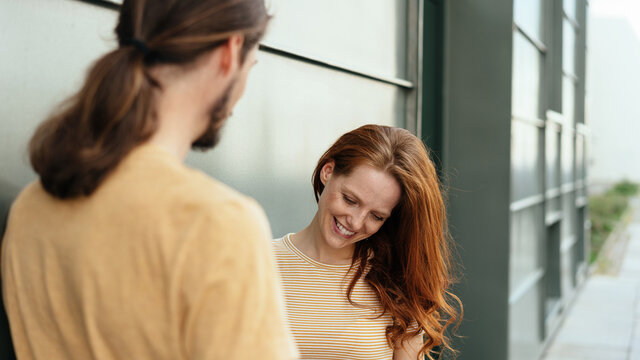 Coy redhead woman chatting to a young man