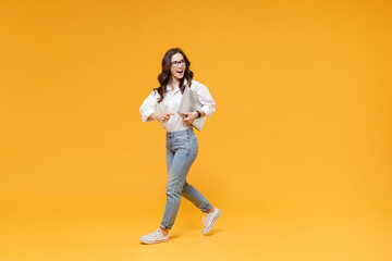 Fototapeta na wymiar Excited business woman in white shirt glasses isolated on yellow background. Achievement career wealth business concept. Mock up copy space. Hold laptop pc computer walking point index finger aside.