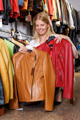 blonde choosing leather jacket on racks