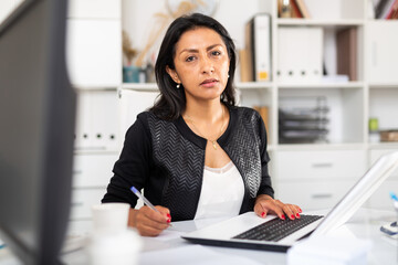 Focused business woman working on laptop in office