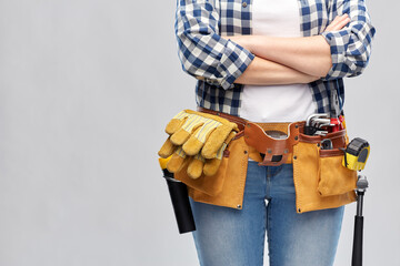 repair, construction and building concept - woman or builder with working tools on belt over grey background