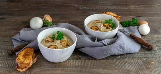 Mushroom cream soup with champignons and croutons on wooden table