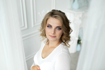 Pregnant woman with wavy hair, close-up portrait. The blonde looks out from behind the tulle
