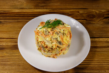 Tasty salad with chicken breast, roasted mushrooms, carrots, grated cheese, eggs and mayonnaise on wooden table