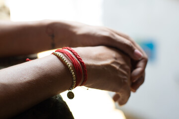 woman hands with red bracelets crossing fingers