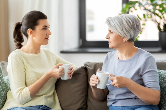 Family, Generation And People Concept - Senior Mother With Adult Daughter Drinking Coffee Or Tea And Talking At Home