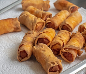 Close up shot of a plate of cooked Chinese / Thai spring rolls. The golden and crispy rolls are drying on a plate ready to eat.