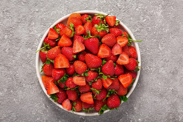Ripe strawberries in bowl healthy eating, top view, gray concrete background, close up
