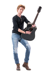 Naklejka premium Self assured handsome guitarist playing acoustic guitar looking at camera. Full body length isolated on white background. 
