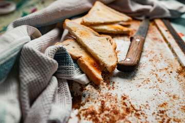 Triangular slices of toasted white bread with a soft texture inside and a crisp crust on the outside on a rusty metal background, next to an old knife with a wooden handle