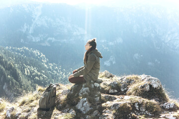 Girl meditates on top of a mountain