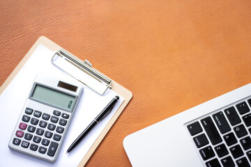Flat lay, top view office table desk.Workspace with calculator,pen,laptop, empty clipboard on leather background.Copy Space for text,Blank to word.Business Finance,Education Technology.Work from home.