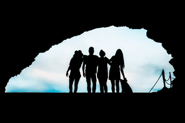 silhouette of a group of friends with dog in a cave in ibiza. friendship and human relations