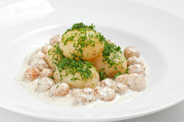 Young potatoes with meatballs and herbs on a white plate