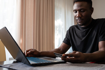 Young Black Man Making Online Purchase Holding Credit Card at Home