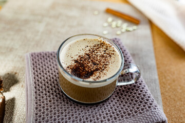Hot cappuccino with chocolate chips on top of the foam, a cinnamon stick, Golden sugar beads and a...
