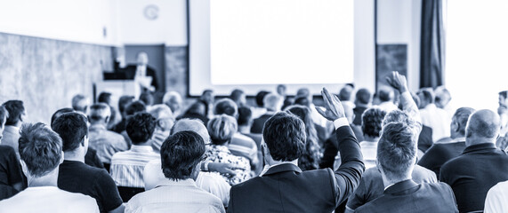 I have a question. Group of business people sitting at the chairs in conference hall. Businessman...