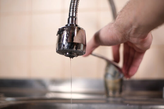 A Man Opens A Faucet In The Kitchen, But No Water Comes. Overlapping Water