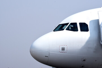 Close-up of airplane nose against blue sky background.