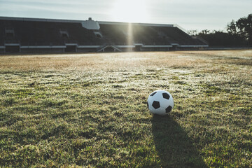 Beautiful view of classic leather soccer ball on green grass field in sports stadium during sunset background. Football arena championship tournament background concept.