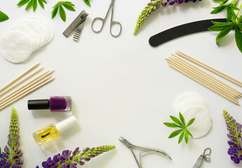 Frame of manicure and pedicure items with lupin flowers on a white background. Space for text