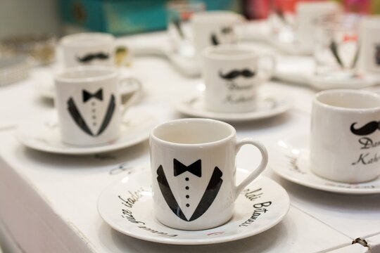 Set of white coffee cups with a suit and mustache design on a table