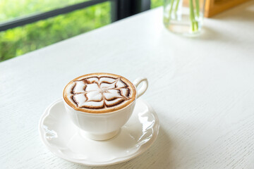 Hot latte art on wooden table at coffee shop.White cup of coffee the best start to any morning at cafe with copy space.