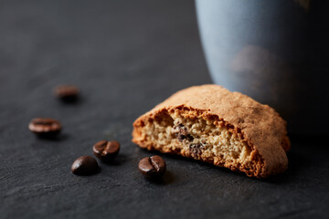 Cantuccini (Italian biscuits) and  roasted coffee beans on dark stone background. Close up. 
