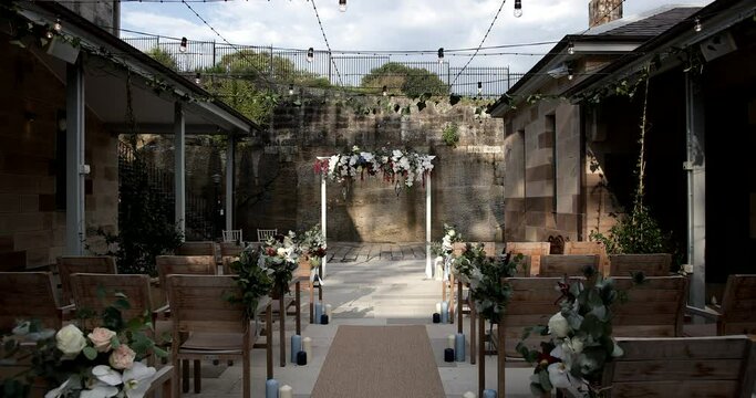 Rustic floral wedding arch at the end of aisle& rows of wooden chairs
